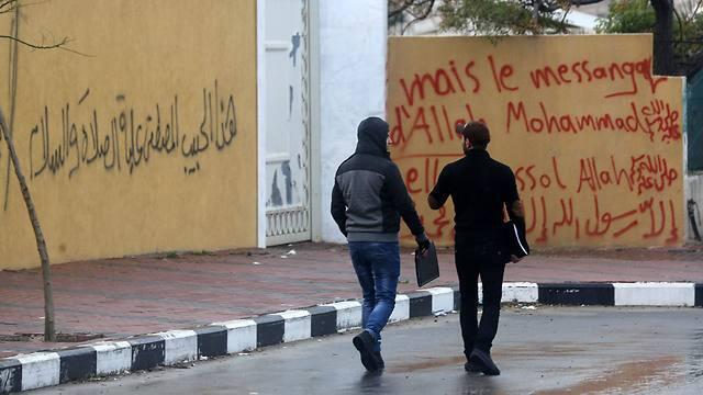 Palestinians walk past walls of French Cultural Center that were painted overnight with graffitti (Photo: AFP) (AFP) Palestinians walk past walls of French Cultural Center that were painted overnight with graffitti (Photo: AFP)