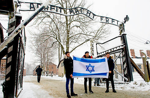 Teens holding the Israeli flag at the entrance to Auschwitz (Photo: MCT)