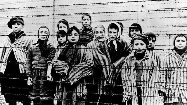 A picture taken just after the liberation by the Soviet army in January, 1945, shows a group of children wearing concentration camp uniforms behind barbed wire fencing in the Auschwitz Nazi concentration camp (Photo: AP)