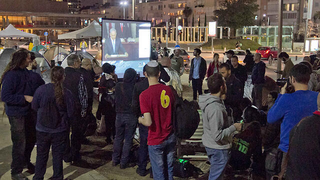 Israelis protesting in Tel Aviv over the coast ovf living watch Netanyahu's speech (Photo: Ido Erez)
