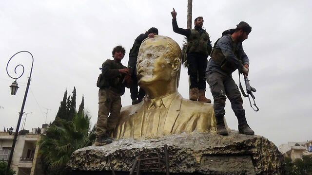 Rebel fighters celebrating on a statue of Hefaz Assad after capturing Idlib (Photo: AFP)