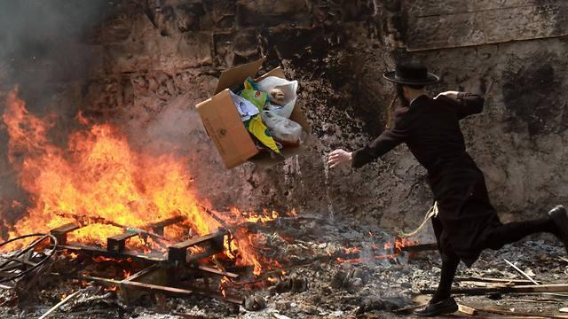 An Ultra-Orthodox Jew throws leavened items onto a fire in Jerusalem during the final preparations before the start of Passover (Photo: AFP) (AFP) An Ultra-Orthodox Jew throws leavened items onto a fire in Jerusalem during the final preparations before the start of Passover (Photo: AFP)