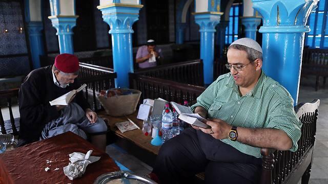 A Tunisian Rabbi and a Jewish man read the Torah inside the ancient Ghriba Synagogue (Photo: EPA) (צילום: EPA) A Tunisian Rabbi and a Jewish man read the Torah inside the ancient Ghriba Synagogue (Photo: EPA)