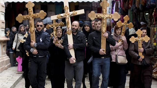 Christian worshipers hold crosses and walk outside the church of the Holy Sepulchre, during the Good Friday procession in the Old City of Jerusalem (Photo: EPA)