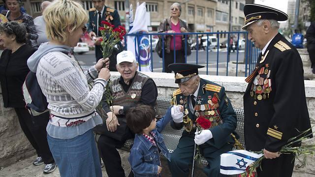 Russian Israeli World War II veterans who served as Russian soldiers from the Soviet Union are greeted by a child during a Victory in Europe Day parade in Jerusalem (Photo: EPA)