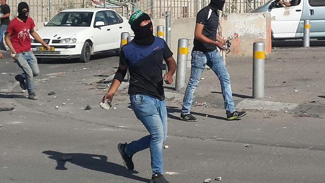 Palestinian youth throw rocks in the Shuafat neighborhood of East Jerusalem Friday. (Photo: Hassan Shalaan)