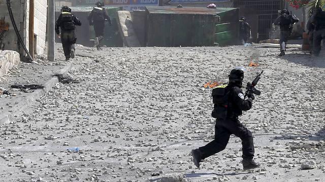 Police navigate a maze of rocks on the street Sunday in East Jerusalem. (Photo: Reuters) (צילום: רויטרס) Police navigate a maze of rocks on the street Sunday in East Jerusalem. (Photo: Reuters)