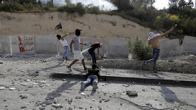 Palestinian youth throw rocks at security forces Sunday. (Photo: Reuters) (צילום: רויטרס) Palestinian youth throw rocks at security forces Sunday. (Photo: Reuters)