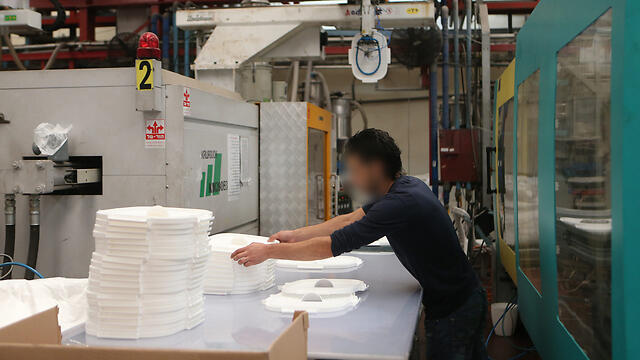 A worker in a factor in Barkan, the West Bank, labels products. (Photo: Alex Kolomoisky)