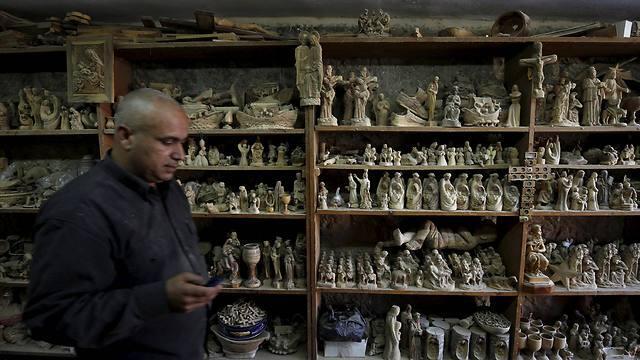 A Palestinian sculptor walks past figures of the Holy Family carved from olive wood in a workshop (Photo: Reuters) (Reuters) A Palestinian sculptor walks past figures of the Holy Family carved from olive wood in a workshop (Photo: Reuters)