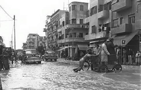People cross the street on a cart on a flooded Shalma Street, 1949 (Photo: Fritz Cohen/GPO) (צילום: פריץ כהן, לע"מ) People cross the street on a cart on a flooded Shalma Street, 1949 (Photo: Fritz Cohen/GPO)