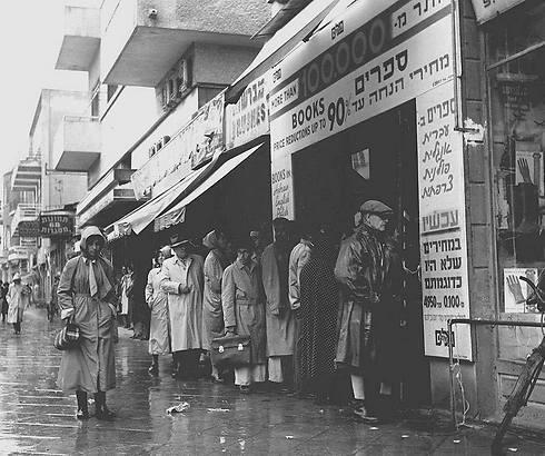 Crowd waits in the rain outside bookstore at 64 Allenby Street, offering books in Hebrew, English, Polish and French at a 90 percent discount, 1955 (Photo: Fritz Cohen/GPO) (צילום: פריץ כהן, לע"מ) Crowd waits in the rain outside bookstore at 64 Allenby Street, offering books in Hebrew, English, Polish and French at a 90 percent discount, 1955 (Photo: Fritz Cohen/GPO)