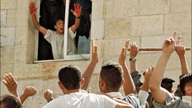 A Palestinian stands in the window of a Ramallah police station in October 2000, displaying the blood of two slain Israeli soldiers on his hands