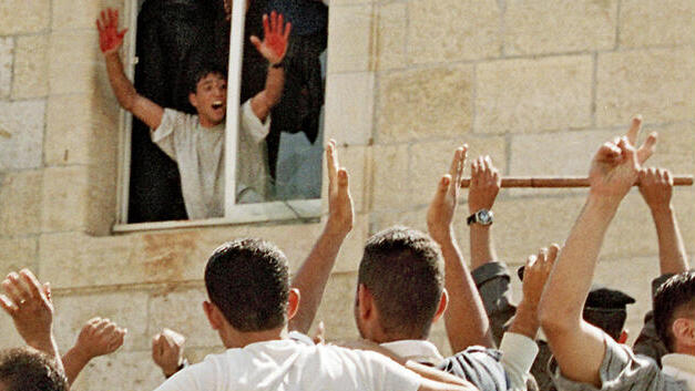 A Palestinian stands in the window of a Ramallah police station in October 2000, displaying the blood of two slain Israeli soldiers on his hands 