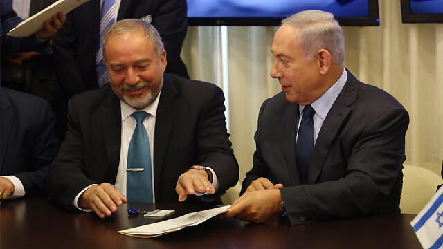 Lieberman and Netanyahu sign the coalition deal (Photo: Gil Yohanan)