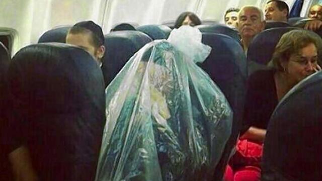 Ultra-Orthodox kohen wraps himself in plastic to prevent from becoming "unpure" as he flies over a cemetary (Photo: New York Daily News)