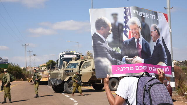 A protester carrying a sign with Mencahem Begin, Anwar Sadat and Jimmy Carter sign the Israel-Egypt Peace Treaty (Photo: Avihu Shapira) (צילום: אביהו שפירא) A protester carrying a sign with Mencahem Begin, Anwar Sadat and Jimmy Carter sign the Israel-Egypt Peace Treaty (Photo: Avihu Shapira)