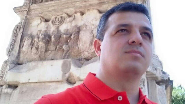 Carmel Shama Hacohen standing before the Arch of Titus