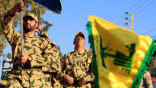 Members of the Lebanon‑based Shiite militia Hezbollah march in camouflage uniforms and carry the group’s yellow flag during a military parade in southern Lebanon, Aug. 18, 2017 