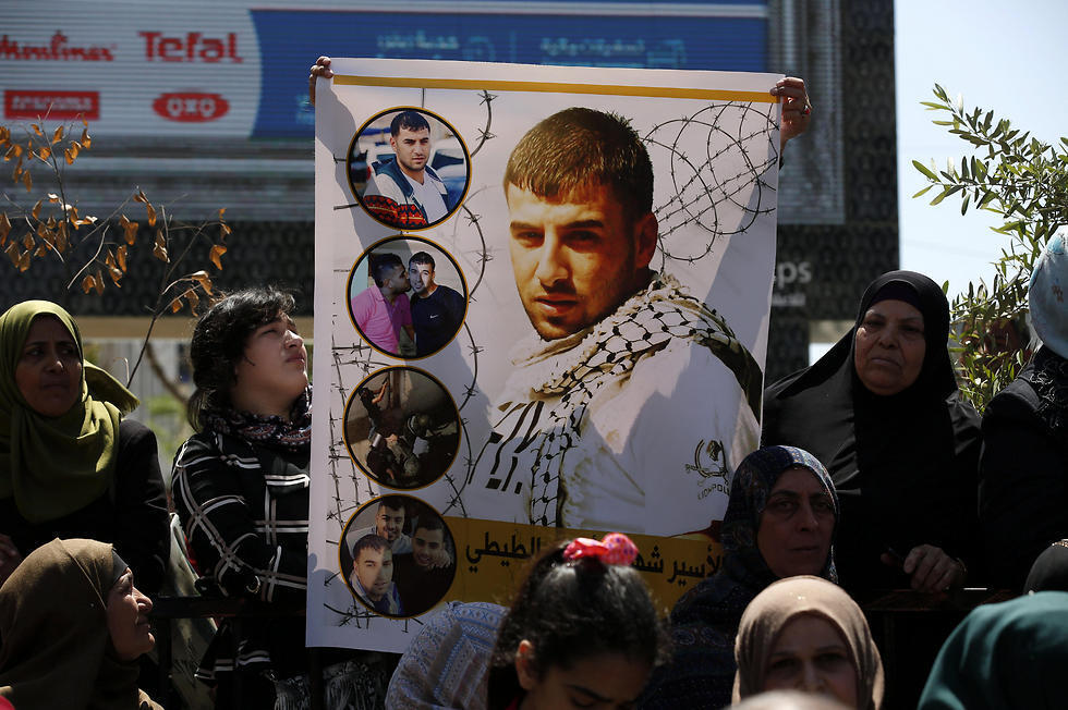 Palestinians hold pictures of their relatives held in Israeli jails during a supportive rally calling for the release of Palestinian prisoners in Israel, in the West Bank city of Hebron on Monday (Photo: EPA)