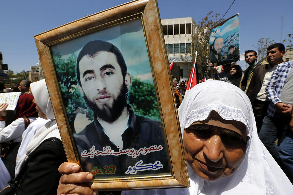 Palestinians hold pictures of their relatives held in Israeli jails during a supportive rally calling for the release of Palestinian prisoners in Israel, in the West Bank city of Hebron on Monday (Photo: EPA)