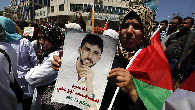 Palestinians hold pictures of their relatives held in Israeli jails during a supportive rally calling for the release of Palestinian prisoners in Israel, in the West Bank city of Hebron on Monday (Photo: EPA)