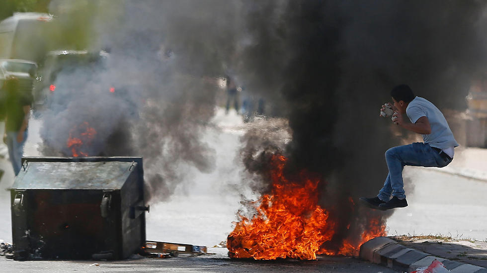 A Palestinian protester jumps near burning tires during clashes with Israeli security forces following a demonstration in the West Bank town of Bethlehem to show their support for Palestinians imprisoned in Israeli jails. (Photo: AFP)