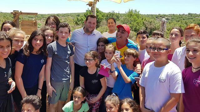 Yuval HaMebulbal (in the center wearing a red hat) with Samaria Regional Council head Dagan and children on the set of the movie (Photo: Roee Hadi) (צילום: רועי חדי) Yuval HaMebulbal (in the center wearing a red hat) with Samaria Regional Council head Dagan and children on the set of the movie (Photo: Roee Hadi)