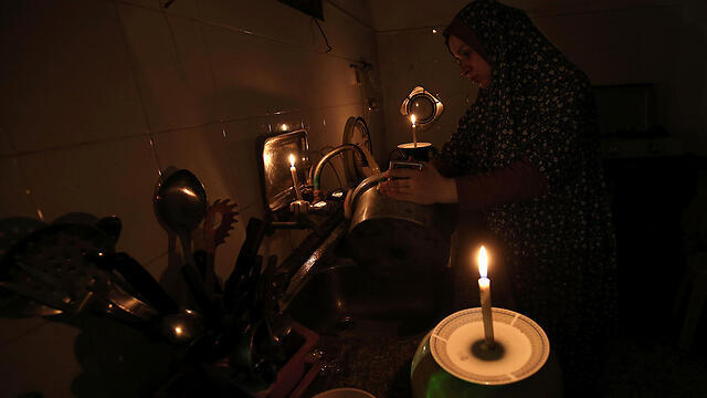 Woman washing dishes to candlelight during power outage (Photo: AFP)