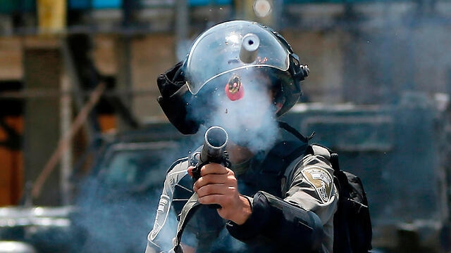 Israeli policeman fires tear gas at Palestinian rioters near Beit El (Photo: AFP) (צילום: AFP) Israeli policeman fires tear gas at Palestinian rioters near Beit El (Photo: AFP)