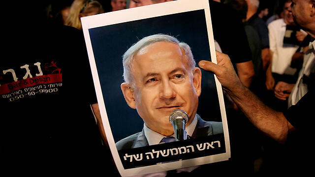 A supporter of Netanyahu's holding a photo of his that reads, 'My prime minister' (Photo: EPA) (צילום: EPA) A supporter of Netanyahu's holding a photo of his that reads, 'My prime minister' (Photo: EPA)