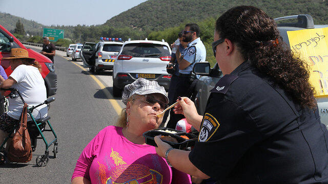 Police Sergeant Neta Shema feeds disabled protestor Iris Haya Zigdon (Photo: Zohar Shahar)