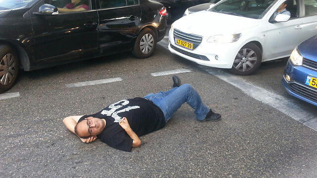 Protestor lying on road to block traffic (Photo: Amir Alon)