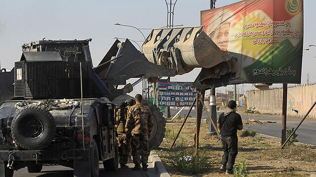 Iraqi forces use an excavator to damage a poster of Iraqi Kurdish president Massud Barzani (צילום: AFP) Iraqi forces use an excavator to damage a poster of Iraqi Kurdish president Massud Barzani