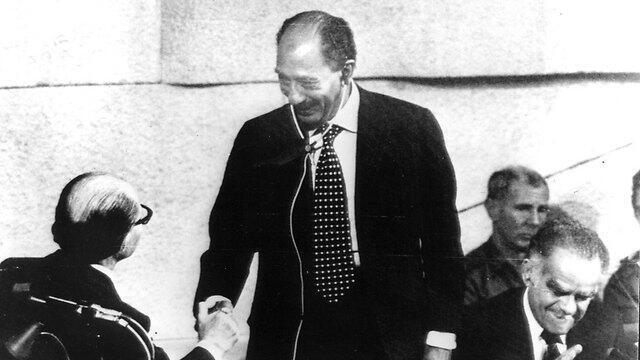 Sadat (C) shaking hands with Begin (L), while Yitzhak Shamir (R), who oversaw Sadat's visit, sits beside them (צילום: AP) Sadat (C) shaking hands with Begin (L), while Yitzhak Shamir (R), who oversaw Sadat's visit, sits beside them