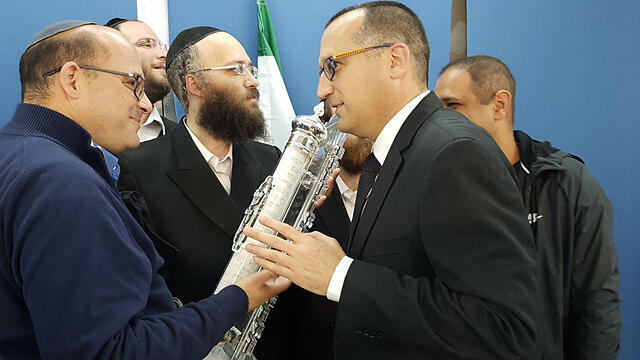 Mayor Kunik kissing a mezuzah after the vote
