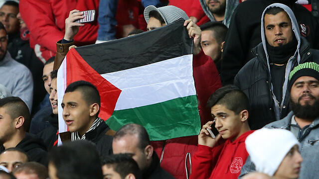 A Bnei Sakhnin supporter holding up the Palestinian flag. The report said the Arab-Israeli team's fans booed a minute's silence for the 10 flood victims
