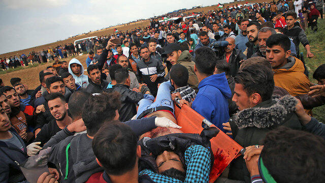 Palestinian protester, shot by IDF sniper, being carried off for treatment (צילום: AFP) Palestinian protester, shot by IDF sniper, being carried off for treatment