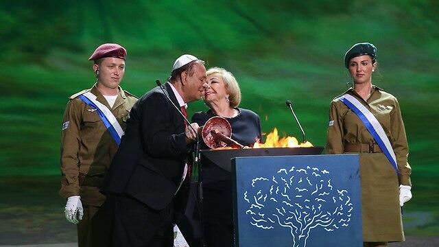Actors Ze'ev Revach and Leah Koenig light a torch