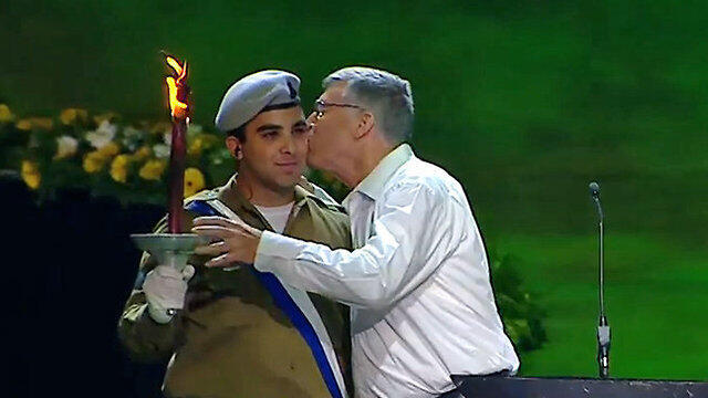 Linguist Dr. Avshalom Kor kissing an IDF soldier as he lights a torch (צילום: אולפני הרצליה) Linguist Dr. Avshalom Kor kissing an IDF soldier as he lights a torch