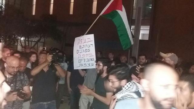 Protester waving sign saying, 'In Gaza you murdered protesters, in Haifa you break bones'