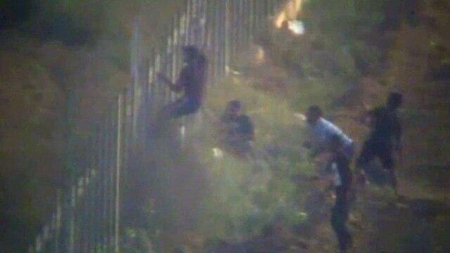File photo. Palestinians scaling the security fence