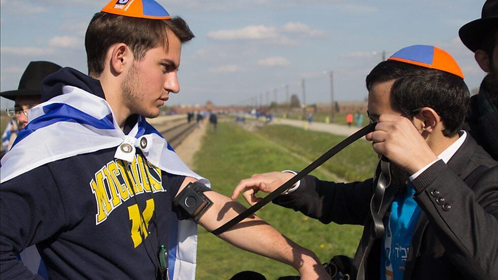Chabad emissaries in Warsaw with young Israeli wrapping Tefillin