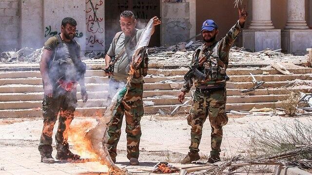 Солдаты армии Асада жгут флаги повстанцев. Фото: AFP
