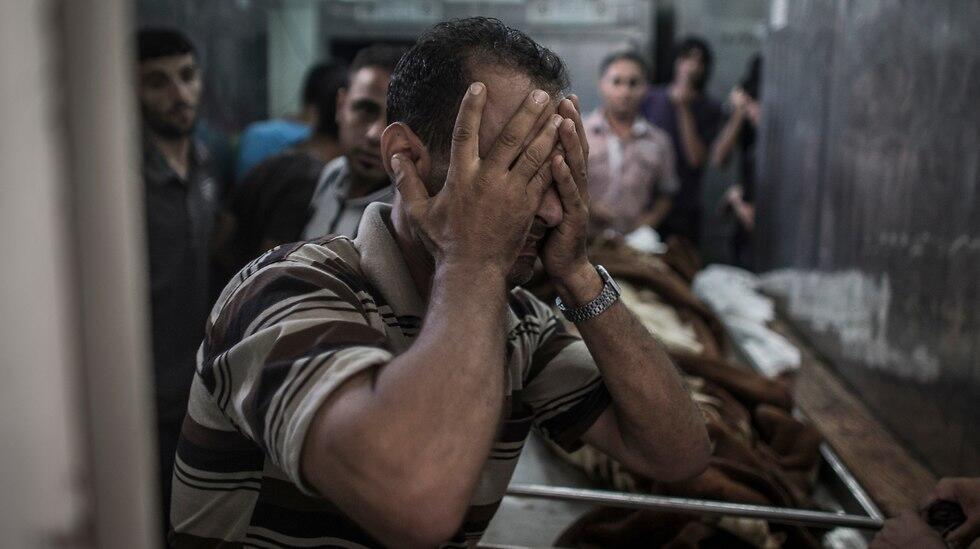Palestinian man cries after seeing body of relative killed during Protective Edge