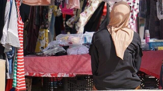 A woman sits on a bench near the market in Rahat