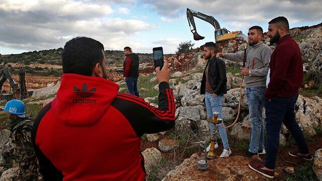 Lebanese villagers take souvenir pictures in front of Israeli excavators in the southern village of Mays al-Jaba (Photo: AP) Lebanese villagers take souvenir pictures in front of Israeli excavators in the southern village of Mays al-Jaba