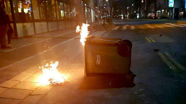 Dozens of protesters burn trash cans