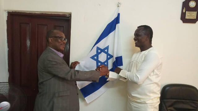 Adikalie Foday Sumah, left, at the Sierra Leone parliament with the Israeli flag