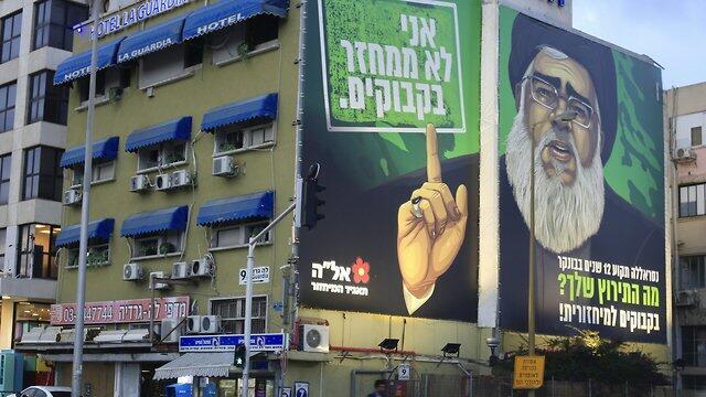 A billboard shows Hezbollah leader Nasrallah as the face of a satirical eye-catching, plastic bottle recycling campaign (Photo: AP) A billboard shows Hezbollah leader Nasrallah as the face of a satirical eye-catching, plastic bottle recycling campaign